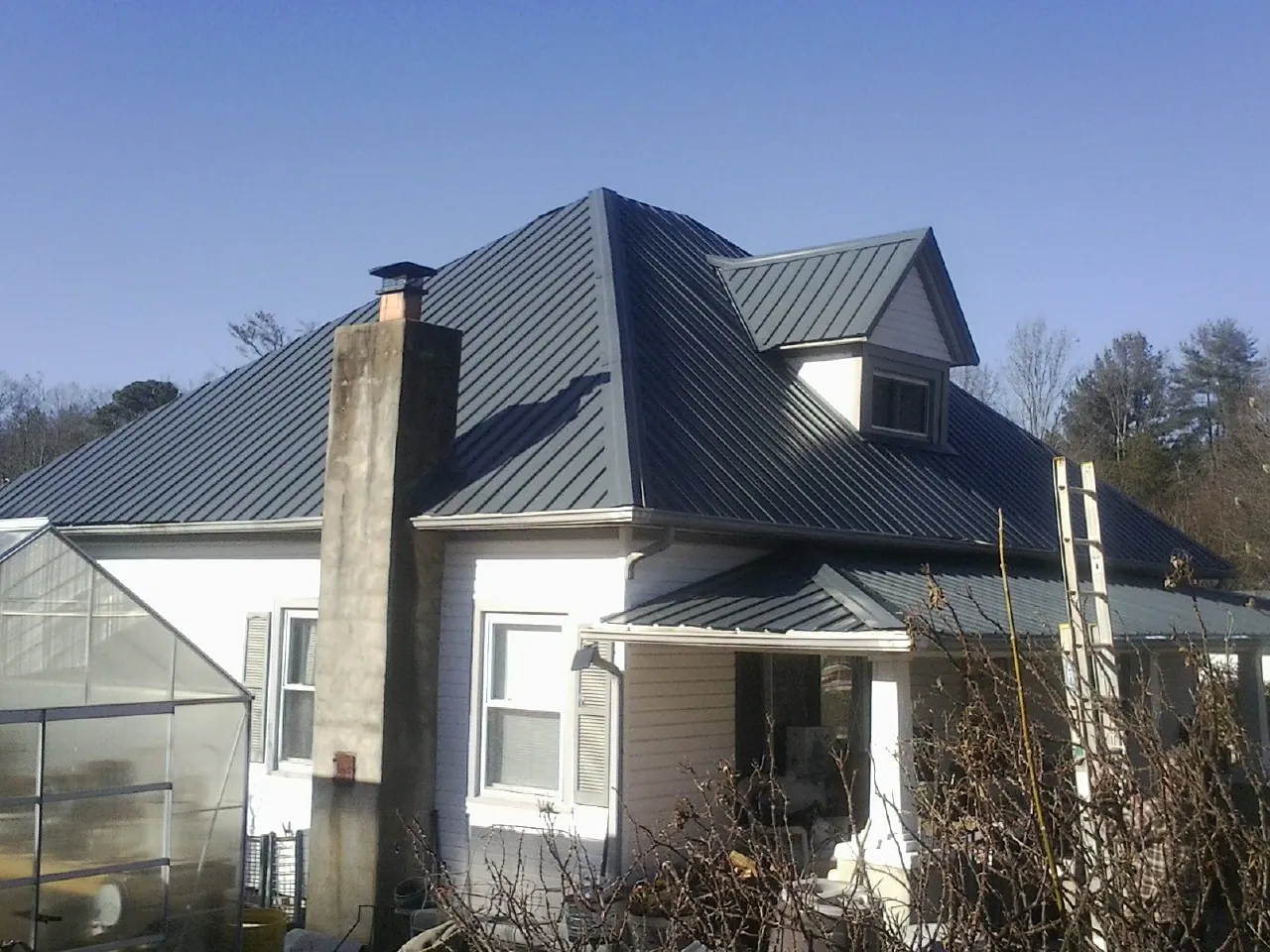 Dark blue standing seam metal roof on a white farmhouse with dormer — Slate & Tile Roof Repair by Roofing Brothers in Ackworth