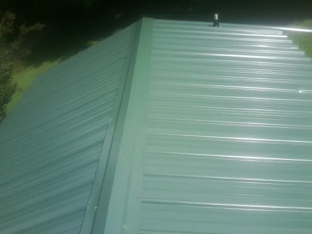 New green metal panels meeting at the ridge of a roof — Flat Roof Repair work by our crew in Ackworth