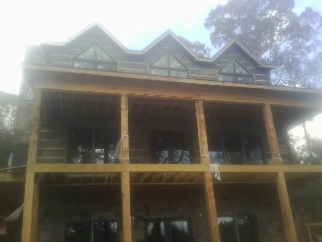 Dormers and porch framing on a large log home under construction — Roof Coating work by our crew in Ackworth
