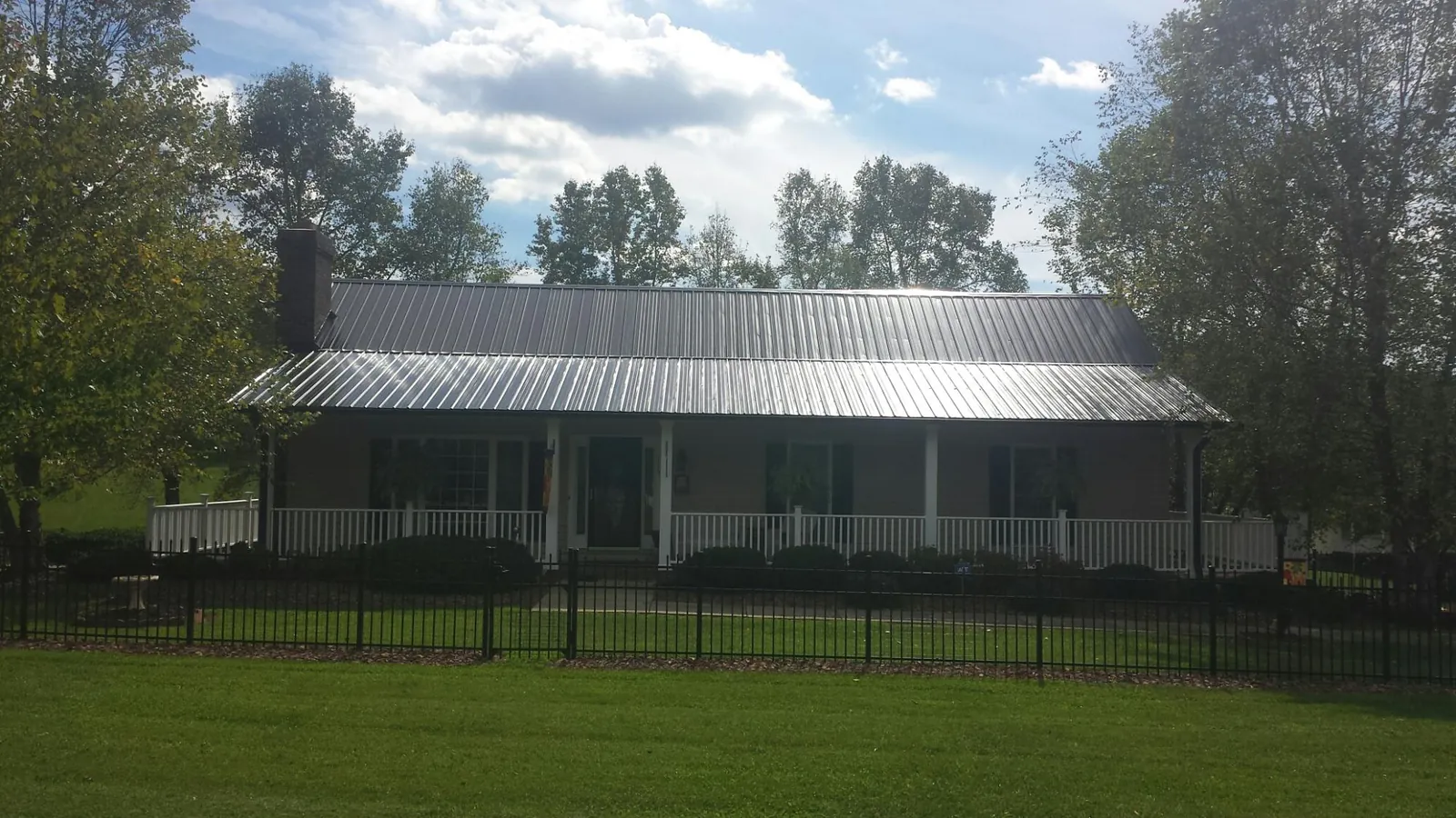Gray metal roof on a brick ranch with a full width front porch — Gutter Guard Installation work by our crew in Ackworth